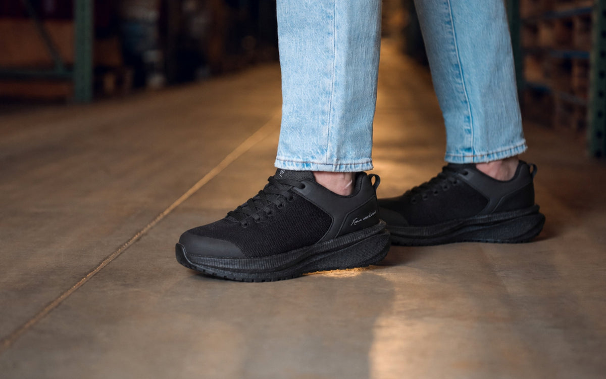 Astra Lite Composite Toe Safety Sneaker for Women — Black Mesh EH PR SRO Rated · lifestyle photo styled in a warehouse setting