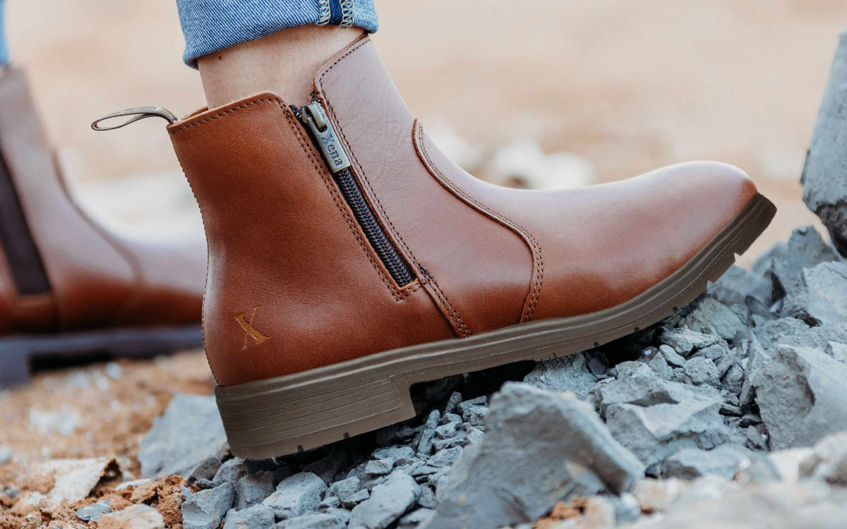 Xena Workwear Omega EH Bourbon Brown women's full-grain leather steel toe safety boots — lifestyle photo on rocky terrain