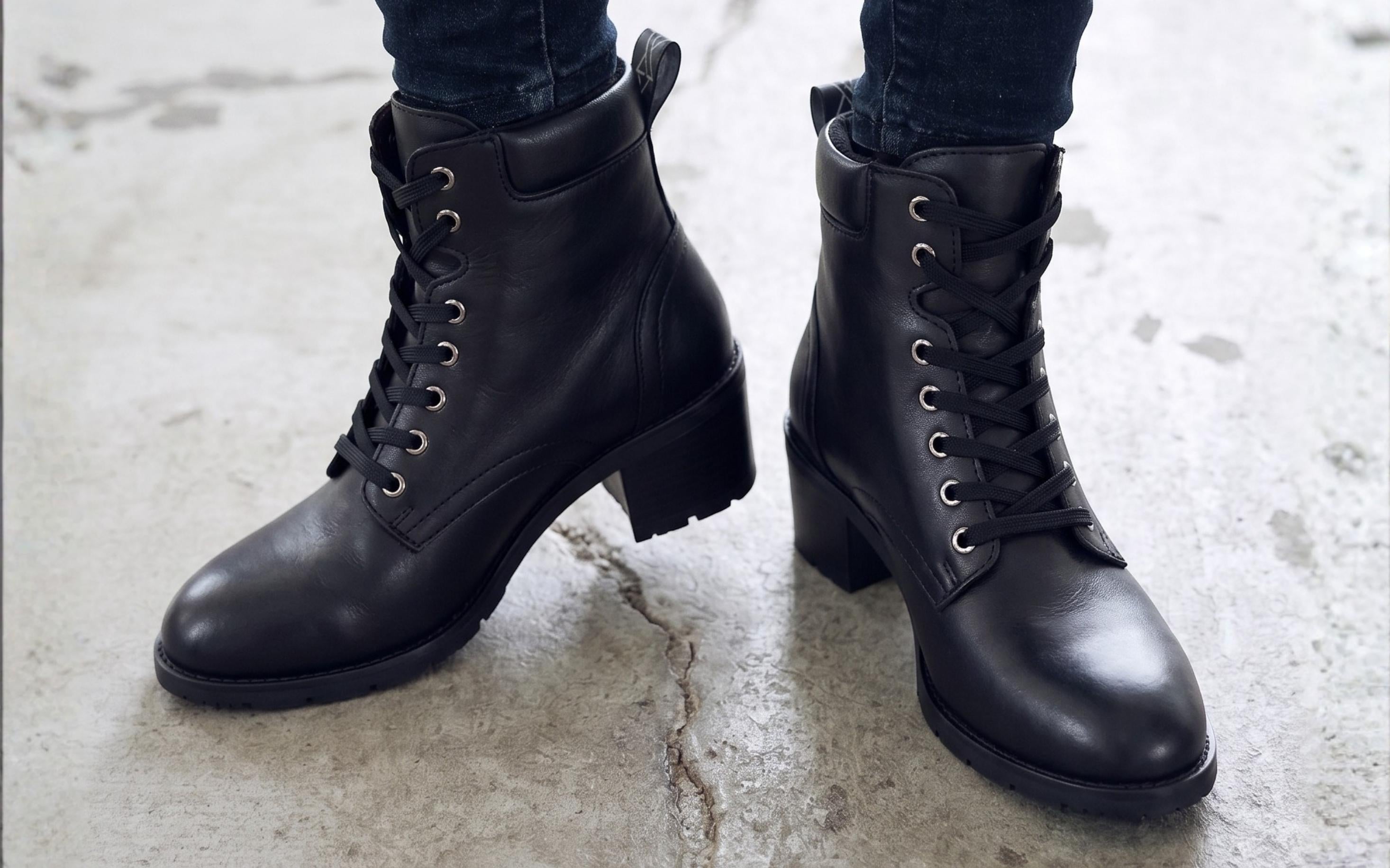 Woman wearing Xena Vega steel-toe safety boots in classic black leather in an industrial workplace